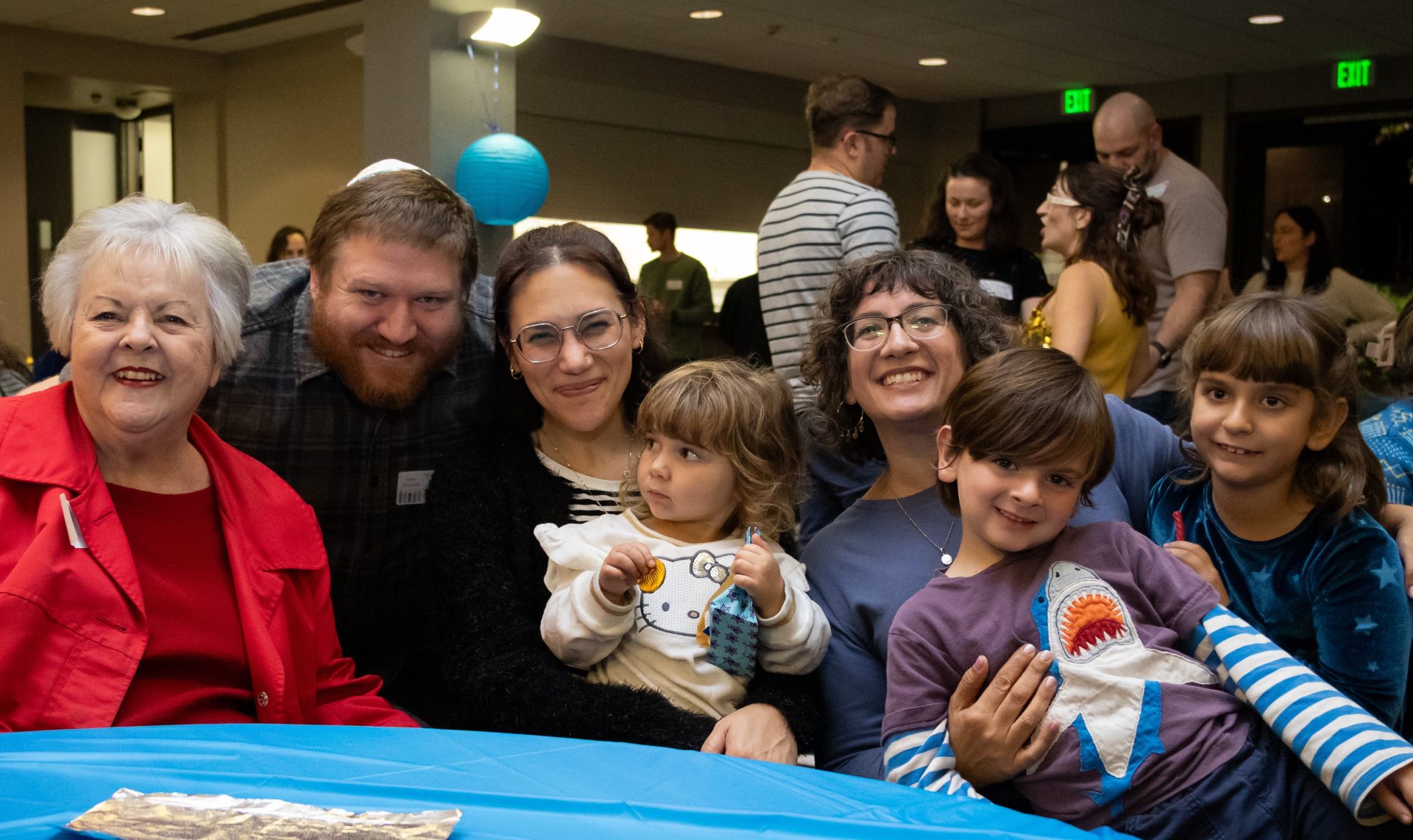 A group of people, including grandparents, parents, and children, sit together at a table.