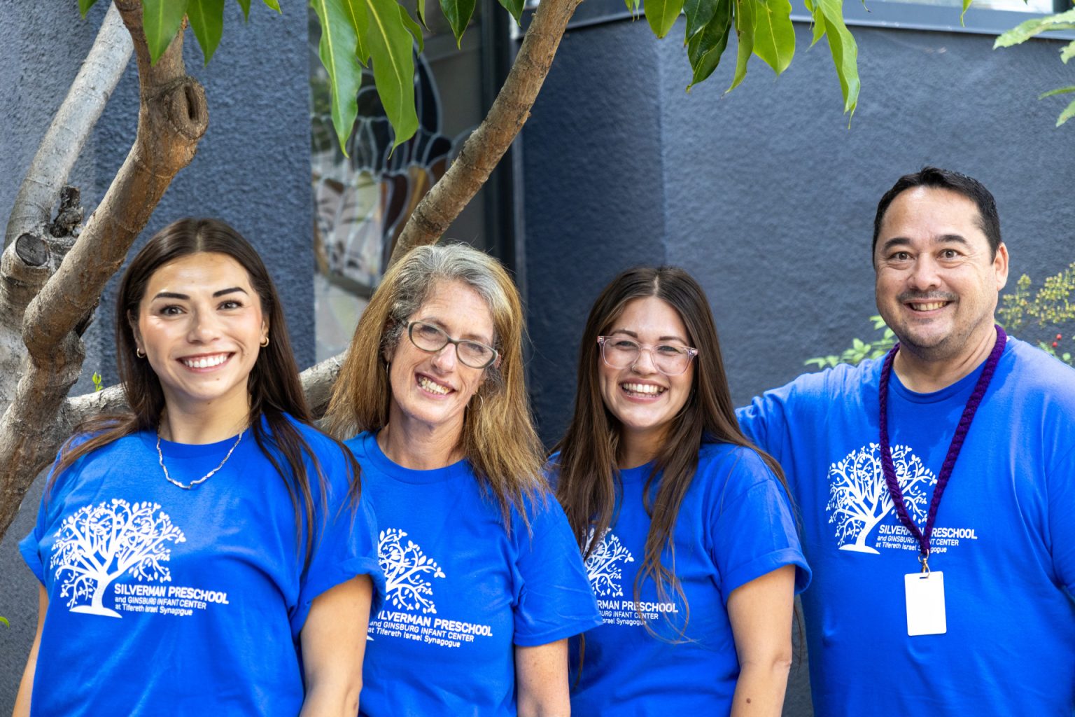 Silverman Preschool 2 year old teachers pose together for a group photo in matching blue shirts.