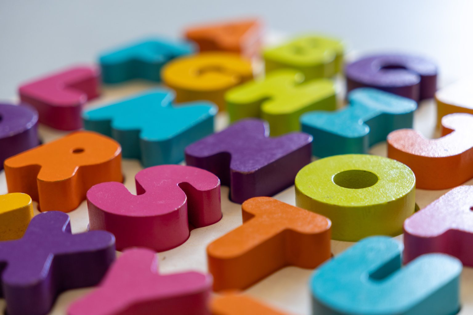Colorful wooden block letters are lined up on a table