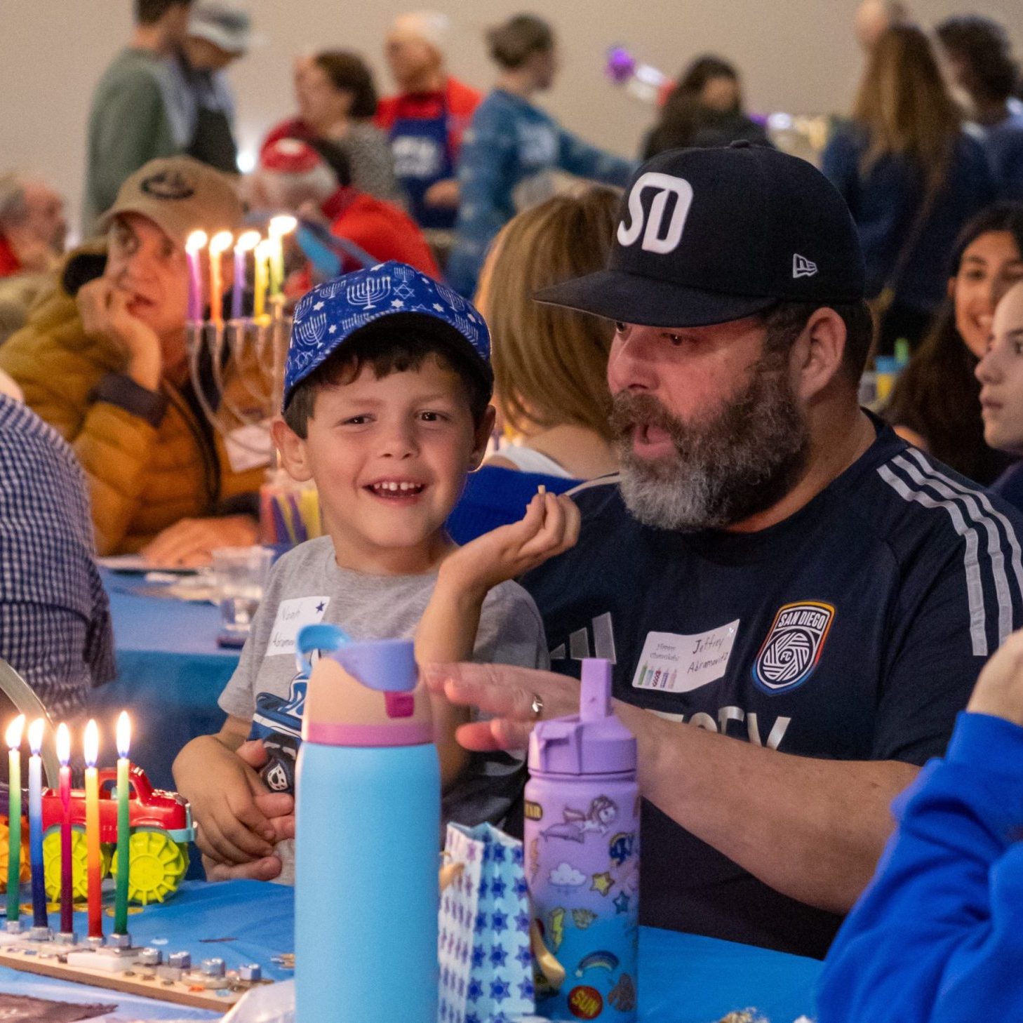 A man and his son sit together and recite the blessings over the Hanukkah candles